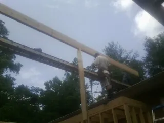Carpenter setting a ridge beam over a new addition frame in New York