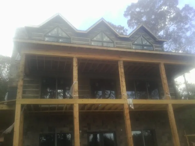 Dormers and porch framing on a large log home under construction — Roof Coating work by our crew in New York