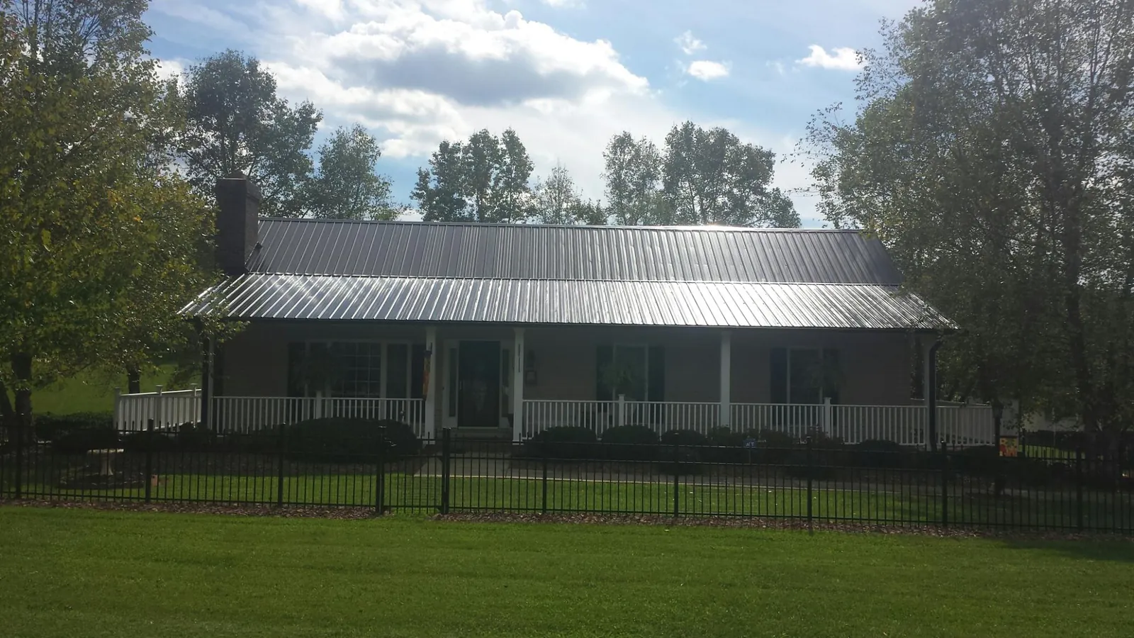 Gray metal roof on a brick ranch with a full width front porch — Gutter Guard Installation work by our crew in New York
