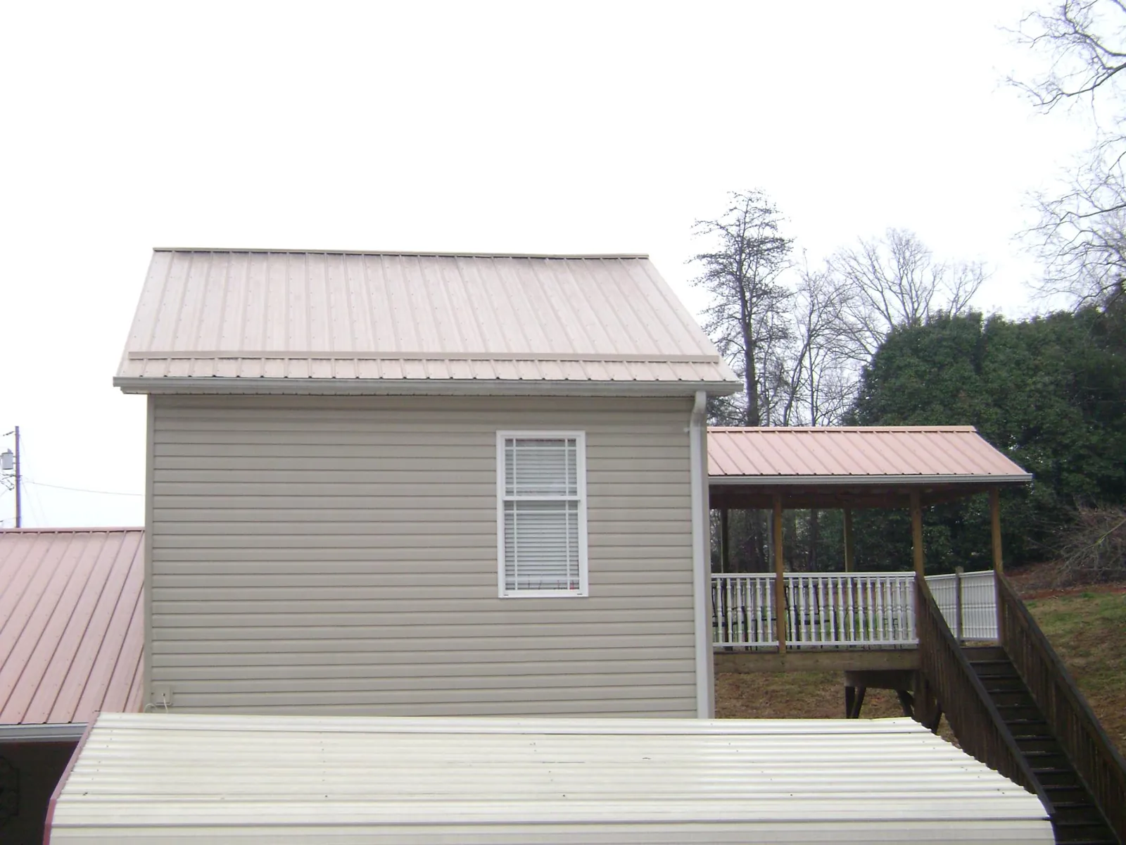 Tan metal roofs on a two story addition and attached porch, from a Roof Replacement job in New York