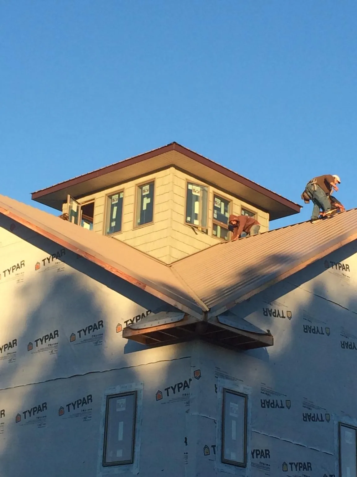 Roofers working around a rooftop cupola on a new metal roof at sunset — Roof Waterproofing in New York by Roofing Brothers